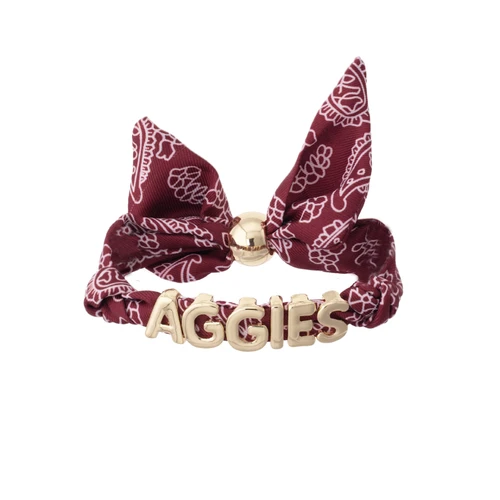 Maroon Texas A&M bandana slider bracelet featuring a white paisley print, knotted bow detail, gold-tone slider, and raised gold AGGIES lettering across the front.