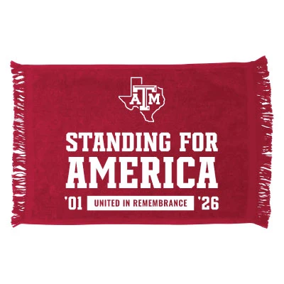 Red Texas A&M game rally towel featuring white Standing for America lettering, a Texas A&M logo inside a Texas outline, ’01 United in Remembrance ’26 details, and fringed edges.