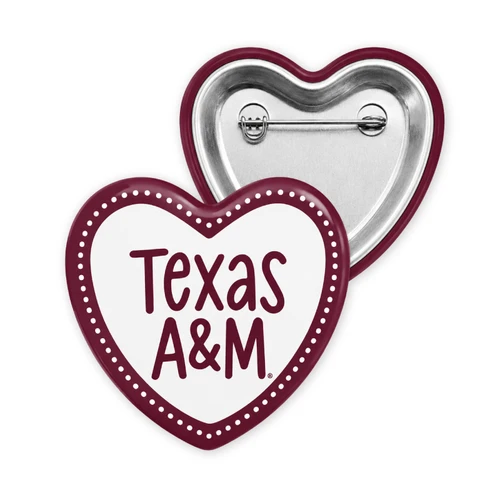 Heart-shaped Texas A&M gameday button featuring a white center, maroon Texas A&M lettering, maroon border with white dotted detailing, and a silver pin backing.