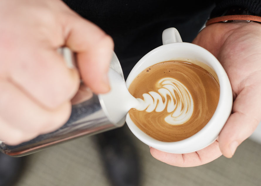 Pouring a rosetta design higher than usual in the cup