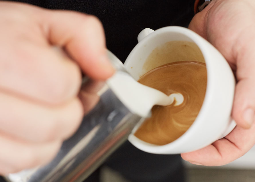 Beginning to make white form on coffee for Swan latte art