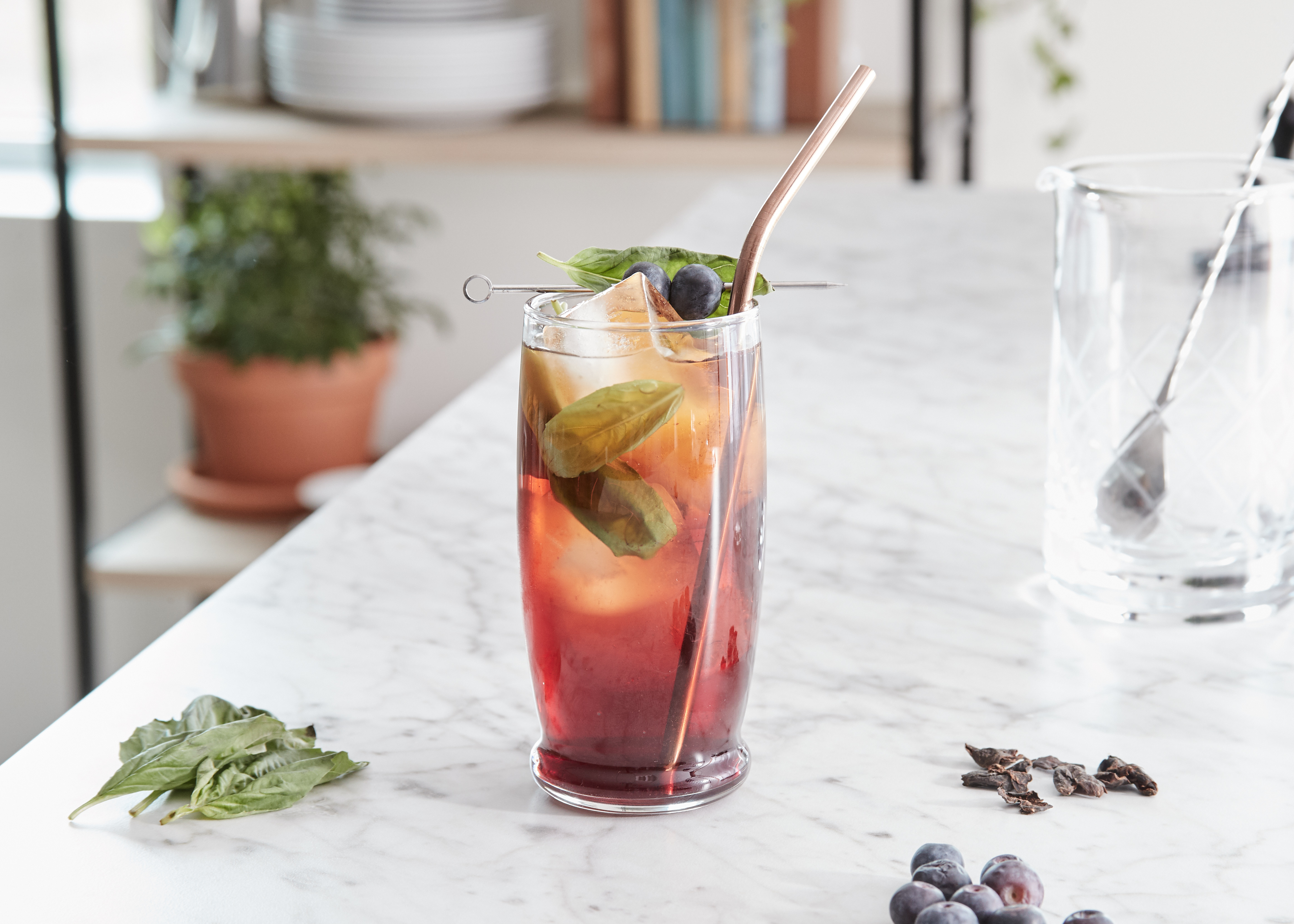 Blueberry + Basil Cascara Sweet Tea served with a straw and ingredients on the table