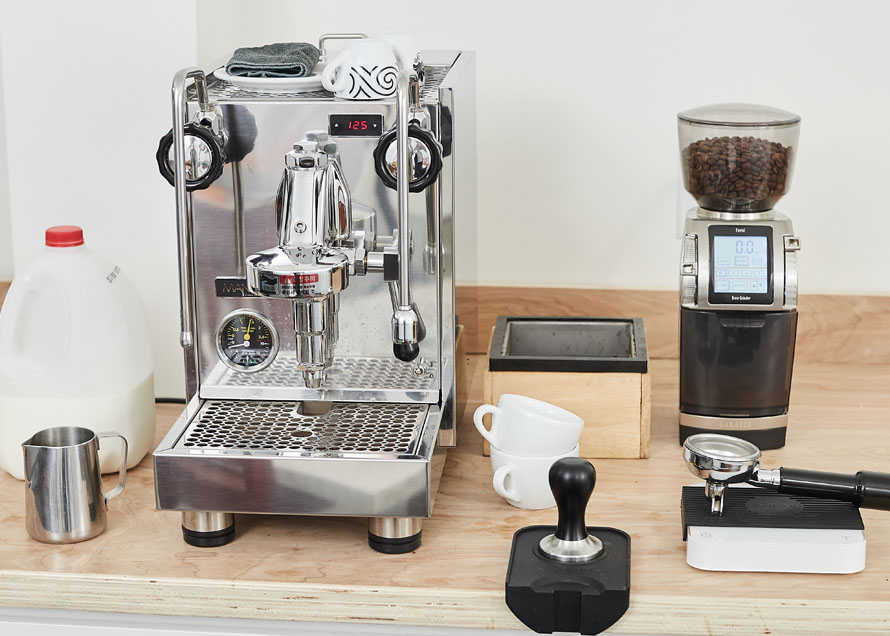 Milk, steaming pitcher, espresso machine, cups, knockbox, tamper, tamp mat, scale, and coffee grinder