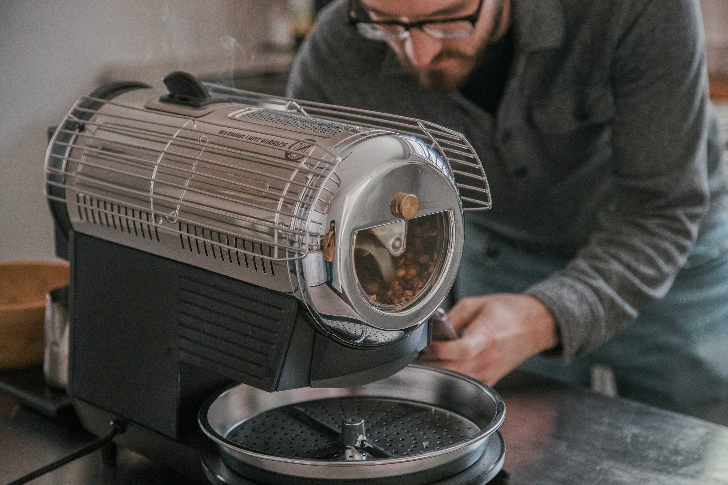 A person looking at their stopwatch, getting ready to make adjustments to the Hottop Coffee Roaster.