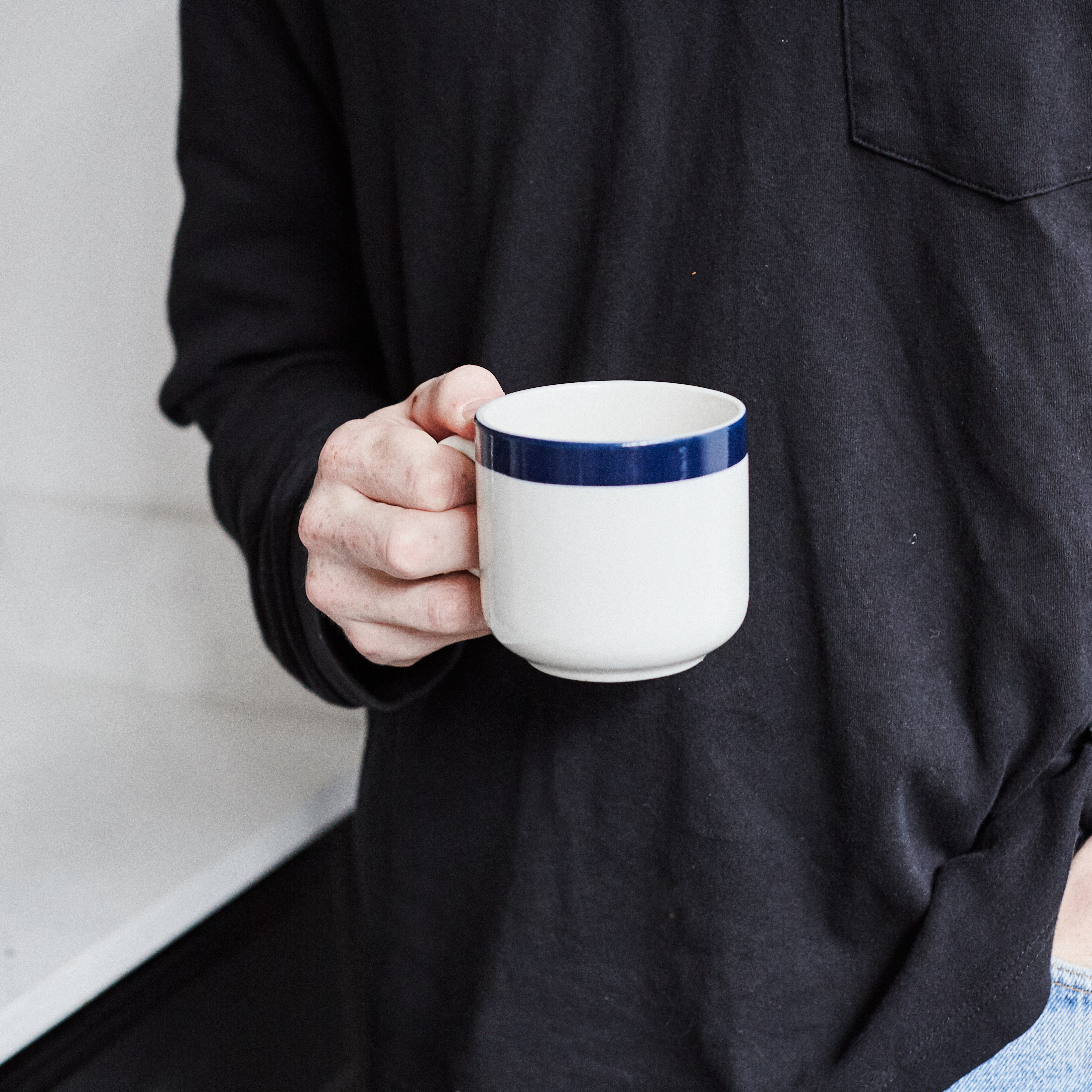 Hand holding blue coffee mug with blue rim