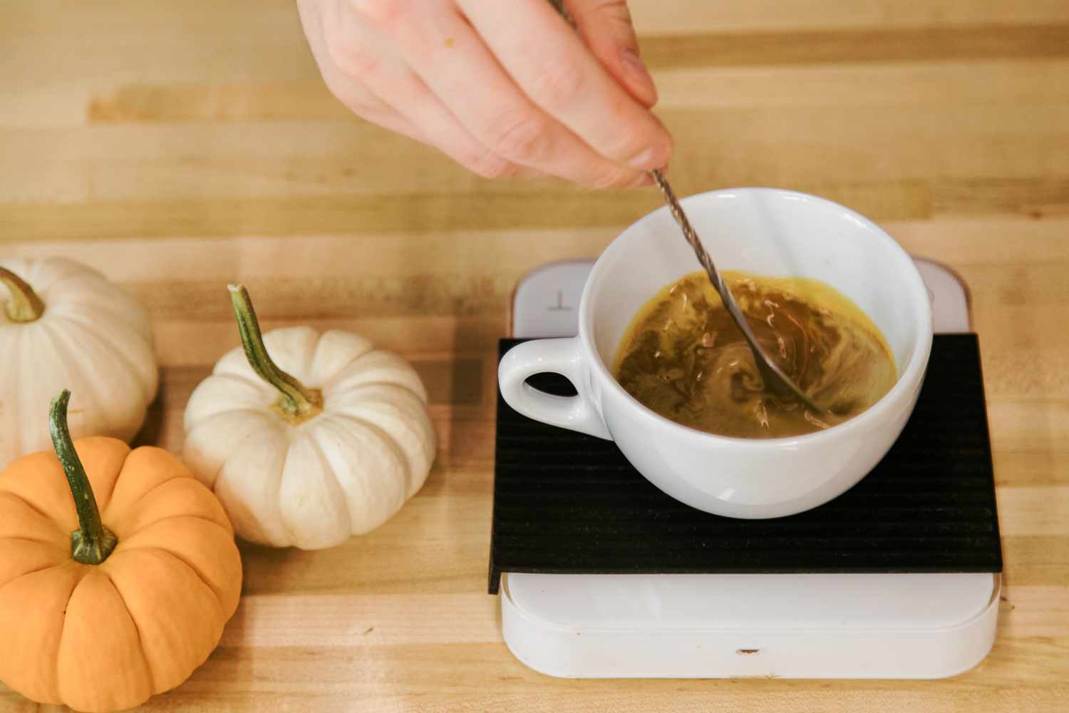 Stirring espresso and pumpkin spice sauce in a cup