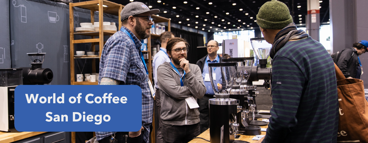 Man in a baseball cap smiling at a customer at a booth at a trade show.