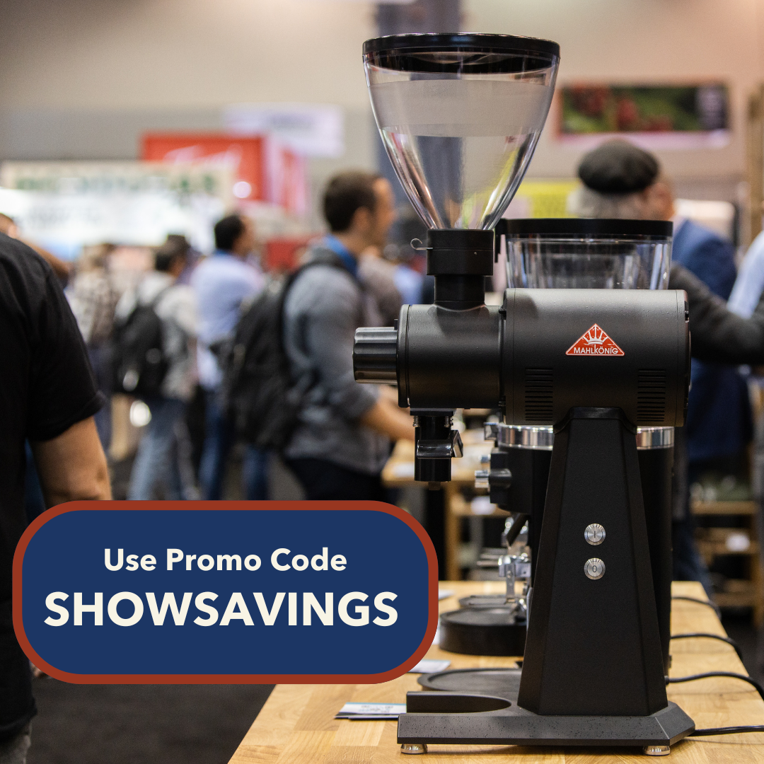 Mahlkonig EK43 sitting on a wooden counter at a trade show with text saying the promo code is SHOWSAVINGS