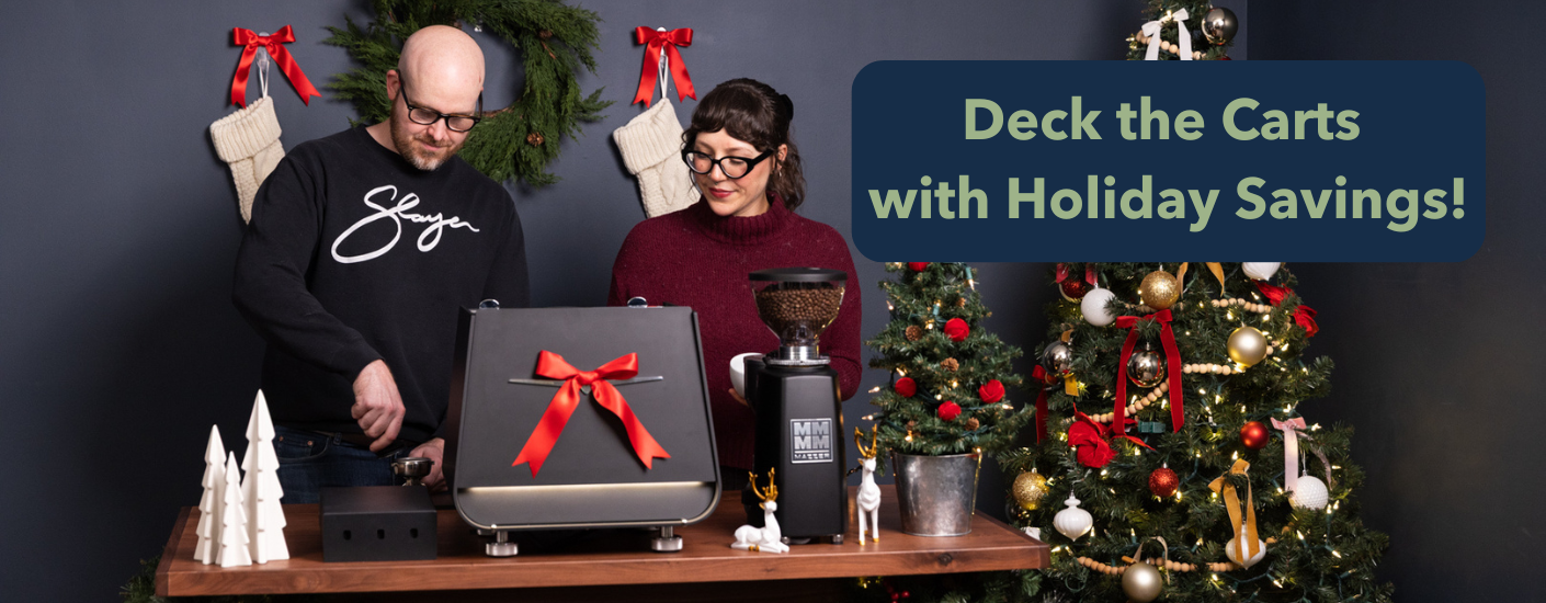 Man and woman standing behind a coffee cart surrounded by Christmas decorations.