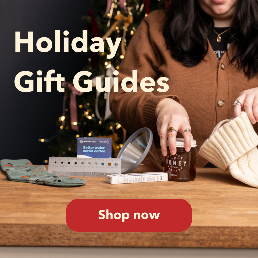 Woman placing a jar of honey in a stocking with third wave water, a brewler, coffee socks, and a brewing cone on a counter. 