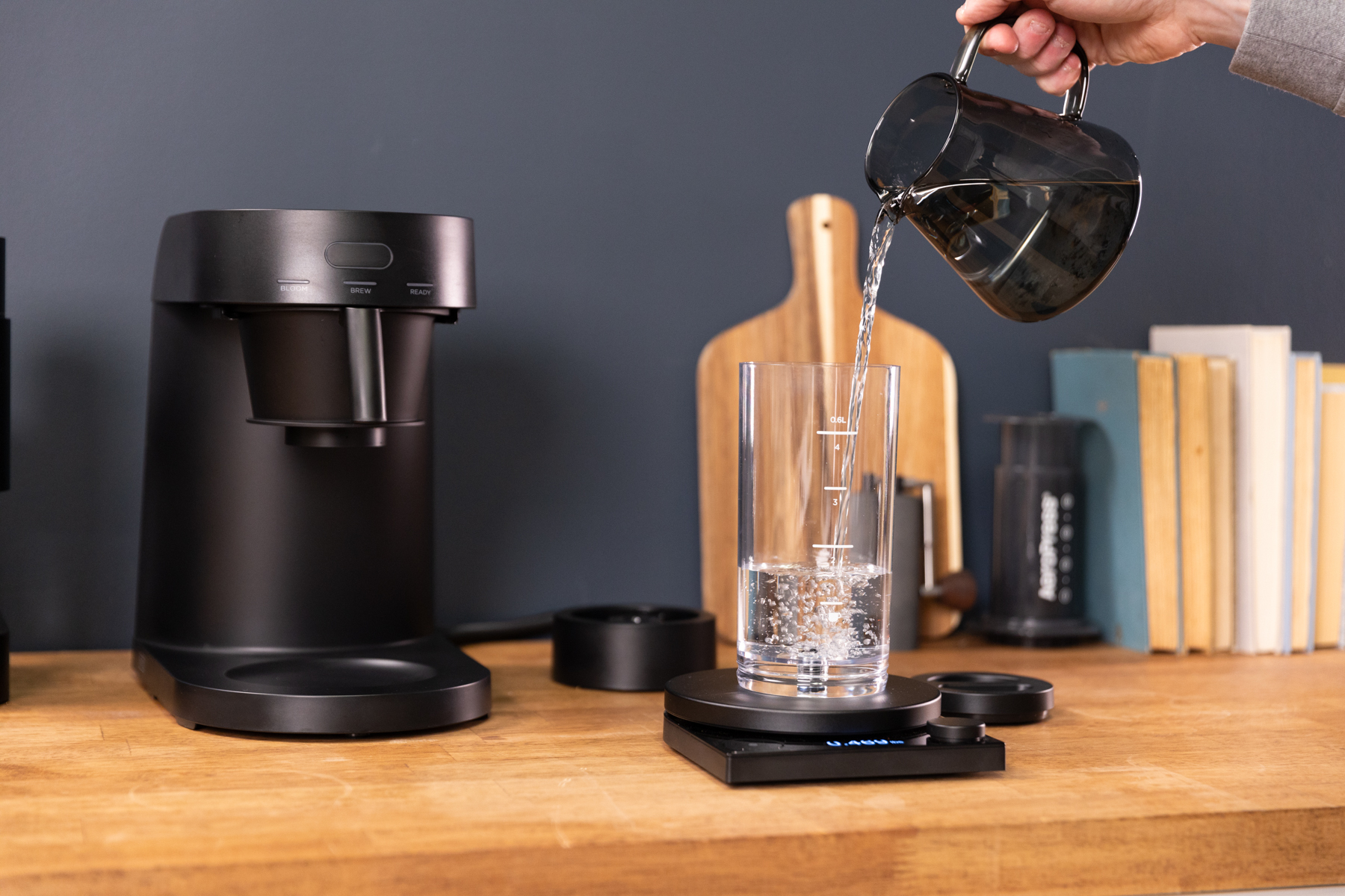 Ratio Four Coffee Brewer in black, filling water reservoir on scale