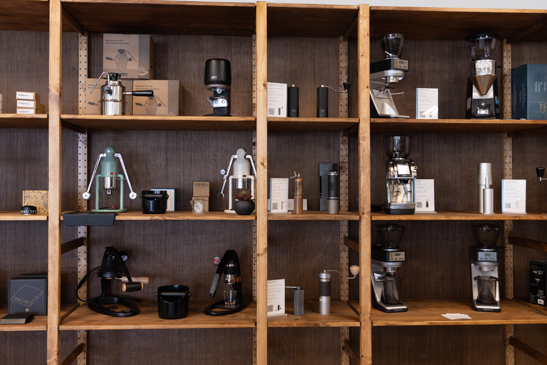 Wooden shelves in a retail space filled with coffee equipment meant to browse and purchase.