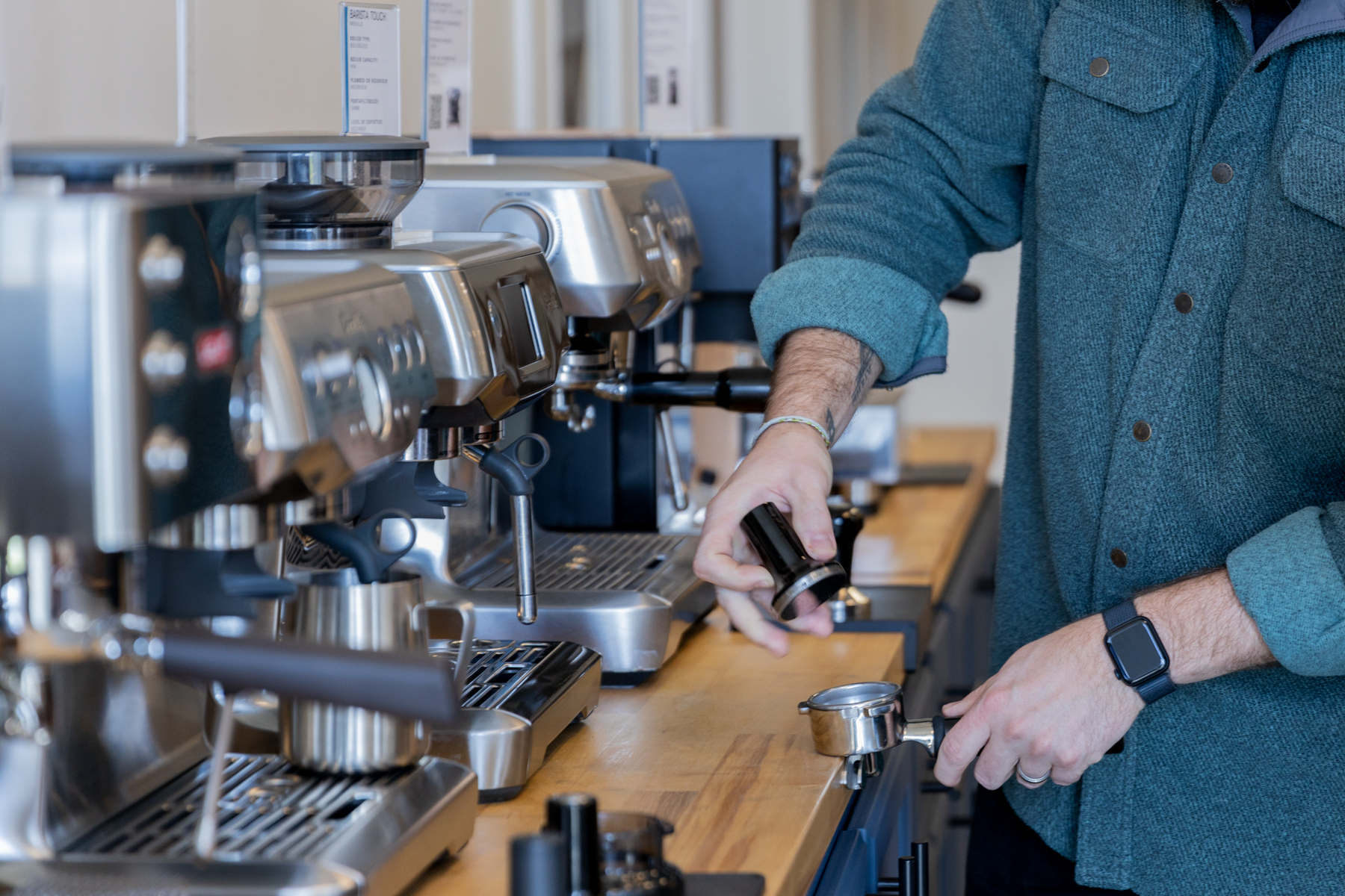 Man's hand holding a tamper ready to tamp coffee in the a portafilter.