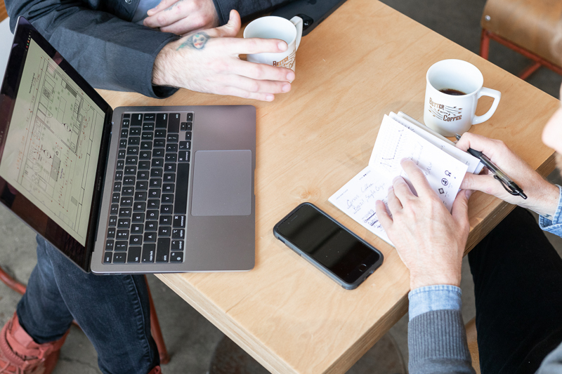 People sitting at a table with coffee notebook and laptop