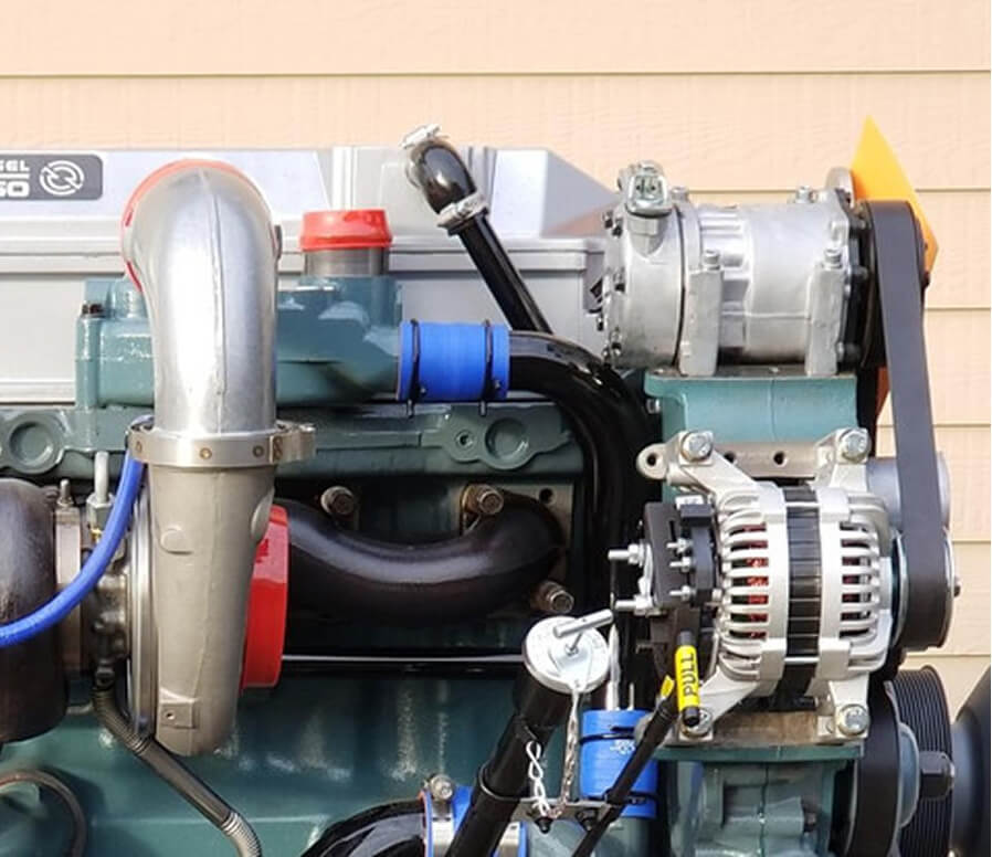 Diesel engine with turbo intake piping, alternator, and accessory components visible during an engine conversion upfit