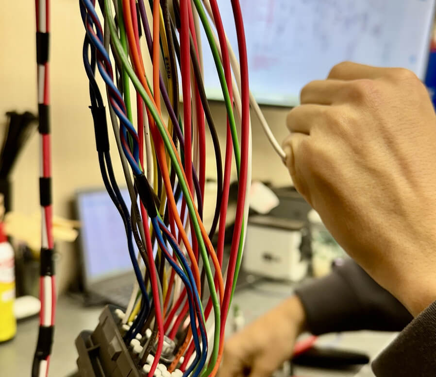 Technician building engine wiring harness by hand at Kustom Truck Parts