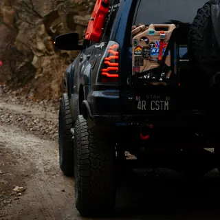 Rear of a dark blue 4Runner with AlphaRex tail lights and a Nguyen Works rear bumper on a rocky trail