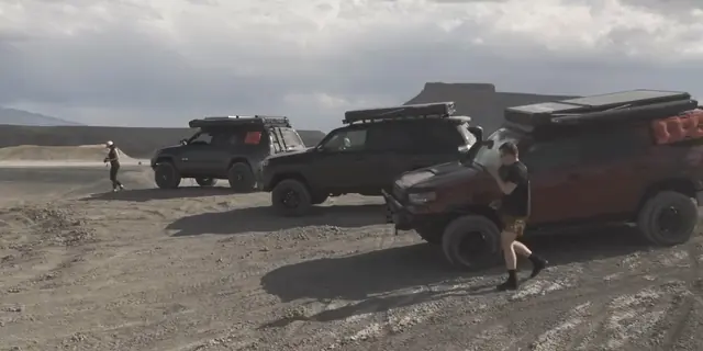 Three 4Runners with roof racks lined up on a dirt flat under a cloudy sky