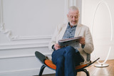 Man wearing reading glasses while reading a newspaper in an armchair