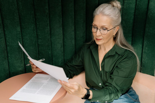 Woman wearing round glasses while reviewing paperwork at a desk