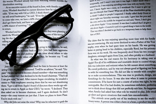 Black rectangular reading glasses lying on an open book