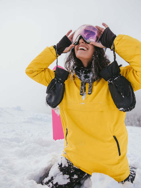Skier in a yellow jacket lifting mirrored snow goggles on a snowy slope