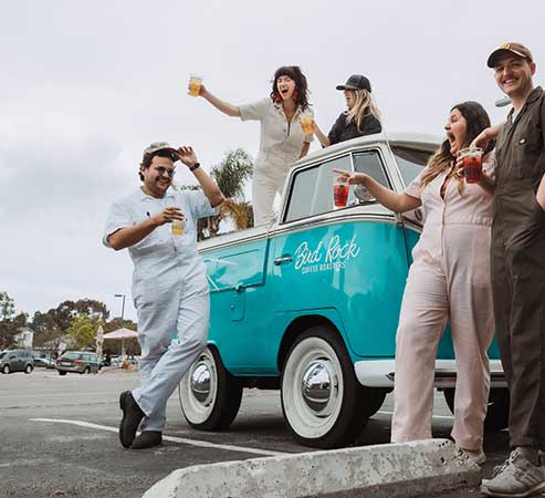 Bird Rock Coffee Team Members hanging out around the Bird Rock VW bus all drinking various coffee shop drinks