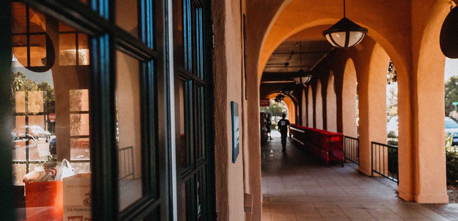 A long exterior tiled hallway with a rustic appearance and stucco walls.