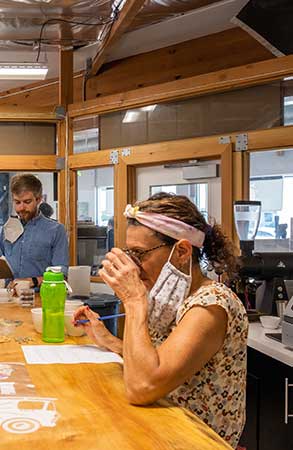 Bird Rock Coffee Team Member holding a white cup to their nose to smell the coffee during tasting and quality control.