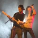 Two musicians performing on stage with smoke effects.