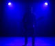 Musician performing under blue stage lights.
