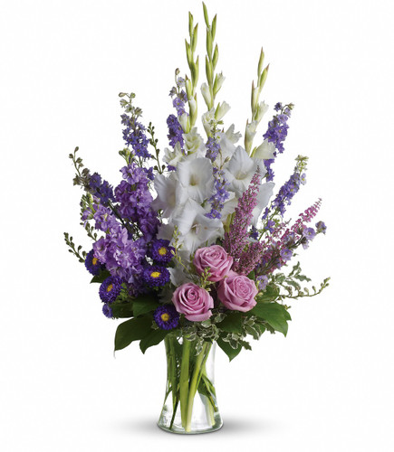 Purple Memories Funeral Arrangement by Sympathy Flower Shop. Lavender and white sympathy flowers make a grand statement in this joyful bouquet. Cherish your memories with this lasting remembrance of lavender larkspur and roses, deep purple asters, pure white gladioli and the softest pink heather. SKU SYM425