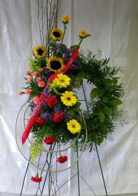 Texas Pride Cowboy Funeral Wreath Flowers from Enchanted Florist - a floral wreath covered in beautiful colorful flowers including happy sunflowers and a red bandanna. Sympathy flowers delivered to local funeral homes in Houston TX and Pasadena TX  RM511