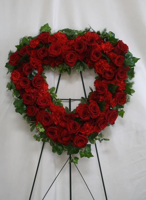 Forever Blessed Red Rose Heart Tribute Spray by Enchanted Florist Pasadena TX. A vibrant red spray of red roses and red carnations designed into a heart shaped sympathy easel. One last spectacular remembrance for that special someone. Approximately 20"H x 20"W STANDARD (size does not include stand)  
SKU RM550