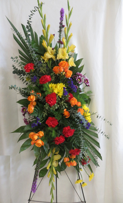 Spectacular Sunset Sympathy Spray of Flowers by Enchanted Florist Pasadena TX. Bright bold colors in a heartwarming sympathy standing spray and includes yellow gladiolas, red carnations, purple liatris, yellow daisies, orange spray roses, and purple daisies. RM537