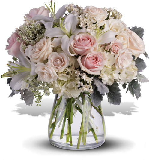 Whispering Love Sympathy Bouquet by Sympathy Flower Shop. Gorgeous flowers such as white, crème and light pink roses, white oriental lilies and filler flowers with a touch of silvery dusty miller, all in a classic clear vase. Your Pearland funeral florist. SKU SYM422