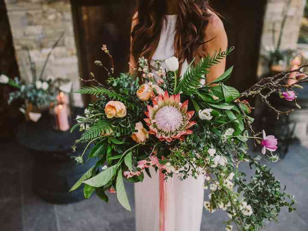 large king protea bouquet image with a variety of other flowers added with greenery.