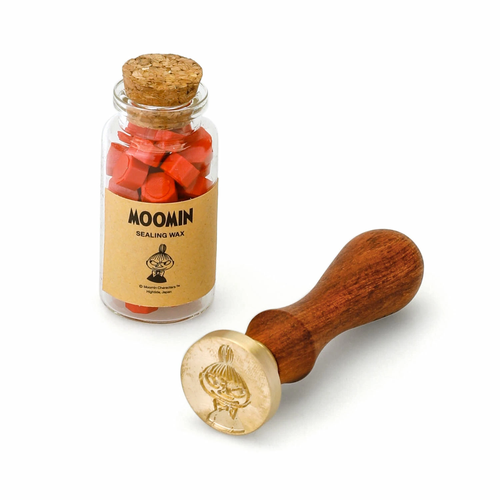HIGHTIDE x Moomin Sealing Stamp Set (Little My) featuring a wooden handle with a 25mm stamp head and a jar of red sealing wax beads in a decorative box. Coffret de sceau à cire HIGHTIDE x Moomin (Petite Mu), comprenant un manche en bois avec un tampon de 25 mm et un pot de perles de cire rouge.