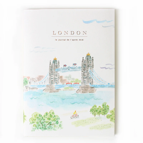 A5 travel journal featuring a watercolor illustration of London's Tower Bridge with a soft blue sky and pink floral accents on a white cover. Carnet de voyage A5 avec une illustration à l'aquarelle du Tower Bridge de Londres, ciel bleu doux et fleurs roses sur une couverture blanche.