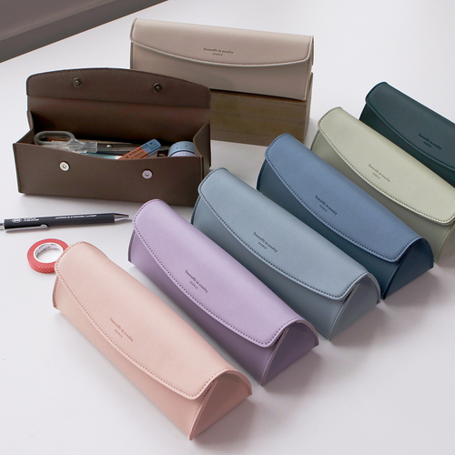 A group of three ICONIC Journey Pen Pouches shown in Beige, Pink, and Pale Blue on a minimalist background. Un groupe de trois trousses à stylos ICONIC Journey présentées en Beige, Rose et Bleu Pâle sur un fond minimaliste.
