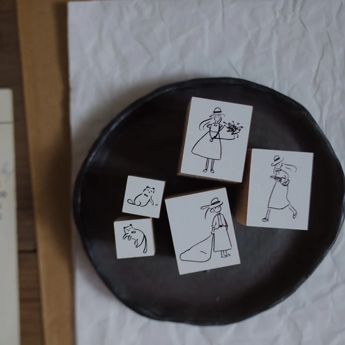 Mr. Eggplants "Her" Rubber Stamp collection featuring three designs: a girl with a flower bouquet, a girl ready to travel, and a girl with baggage, all on wooden handles. Collection de tampons en bois Mr. Eggplants "Her" comprenant trois modèles : une fille avec un bouquet, une fille prête à partir, et une fille avec ses bagages.