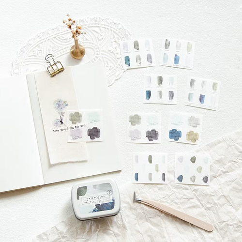 MU Mini Tin Palette Stickers 06 Serene Blue. A small tin with 20 washi paper stickers featuring blue dots, stripes, and geometric swatch patterns. Autocollants MU Mini Tin Palette 06 Serene Blue. Une petite boîte avec 20 autocollants en papier washi aux motifs de pois, rayures et nuances de bleu.