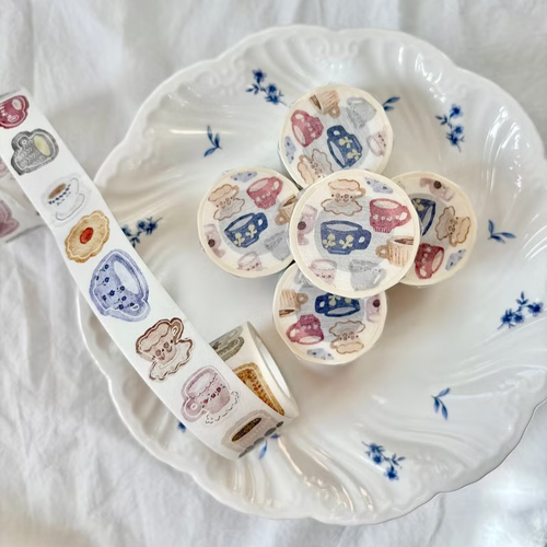 Pion Die-Cut Washi Tape Afternoon Tea. A 2.5cm wide washi tape featuring illustrated tea sets, cakes, and girls with pre-cut edges for easy peeling. Ruban adhésif Washi découpé Pion Afternoon Tea (下午茶). Un ruban de 2,5 cm illustrant des services à thé, des gâteaux et des filles avec des bords prédécoupés.