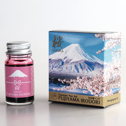 Teranishi Mt. Fuji Fountain Pen Ink in Sakura Pink. A 12ml glass bottle of soft red-pink ink with a label featuring a Mt. Fuji and cherry blossom motif. Encre pour stylo-plume Teranishi Mt. Fuji en Sakura Rose. Un flacon de 12 ml d'encre rose-rouge doux avec une étiquette illustrant le Mont Fuji et les cerisiers.