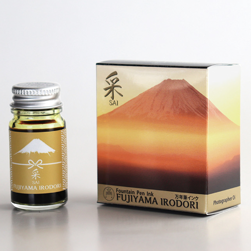 Teranishi Mt. Fuji Fountain Pen Ink in Sai Yellow. A 12ml glass bottle of brilliant golden-yellow ink with a yellow Mt. Fuji illustration on the label. Encre pour stylo-plume Teranishi Mt. Fuji en Sai Jaune. Un flacon de 12 ml d'encre jaune doré éclatant avec une illustration du Mont Fuji jaune sur l'étiquette.
