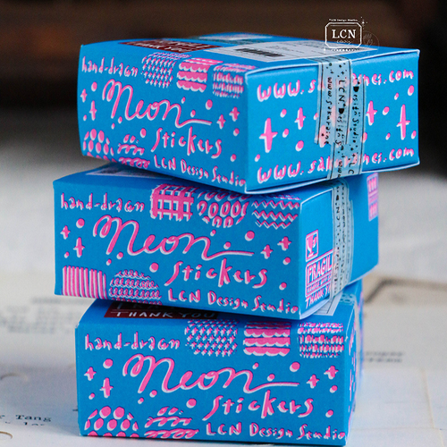 Lin Chia Ning "Sticker Club Neon" set. A small blue and pink carton containing 70 neon-colored flake stickers in PET and matte paper. Set "Sticker Club Neon" par Lin Chia Ning. Une petite boîte en carton contenant 70 autocollants néon bleus et roses en PET et papier mat.