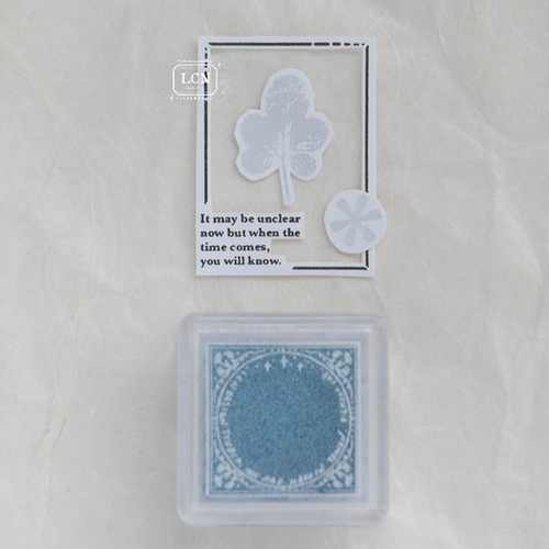 A small, square pale blue ink pad labeled Morning Mist by artist Lin Chia Ning. Un petit encreur carré bleu pâle nommé Morning Mist, créé par l'artiste Lin Chia Ning.