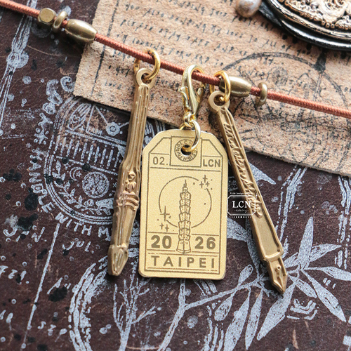 A limited edition Lin Chia Ning brass charm featuring the Taipei 101 tower and the text "2026 Taipei" for Zakka Joshi Haku. Une breloque en laiton Lin Chia Ning en édition limitée représentant la tour Taipei 101 et l'inscription "2026 Taipei" pour le salon Zakka Joshi Haku.