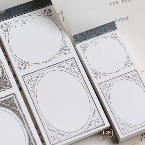 A Lin Chia Ning notepad featuring two different ornate vintage photo frame designs printed in letterpress. Un bloc-notes Lin Chia Ning présentant deux motifs différents de cadres photo anciens ornés, imprimés en typographie (letterpress).