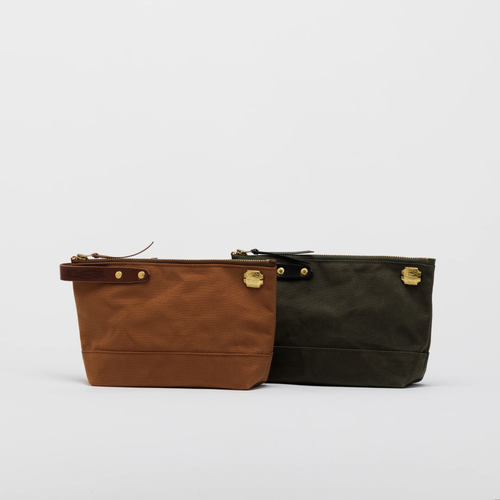 THE SUPERIOR LABOR Paraffin Canvas Pouch #03. A long, rugged waxed canvas organizer pouch with a brass zipper, shown in 6 vintage-inspired colors. Pochette en toile paraffinée #03 par THE SUPERIOR LABOR. Une grande trousse robuste en toile cirée avec zip en laiton, disponible en 6 couleurs vintage.